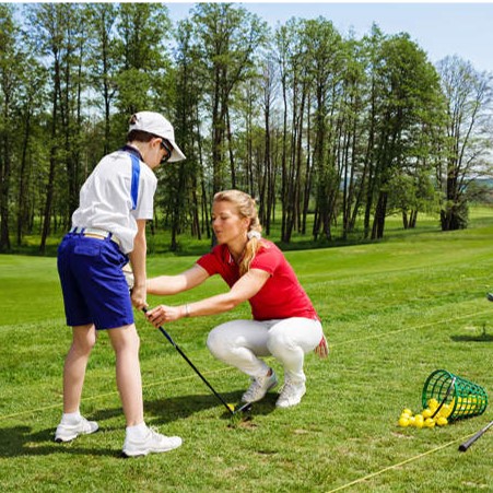 Coach providing golf instruction to young participant